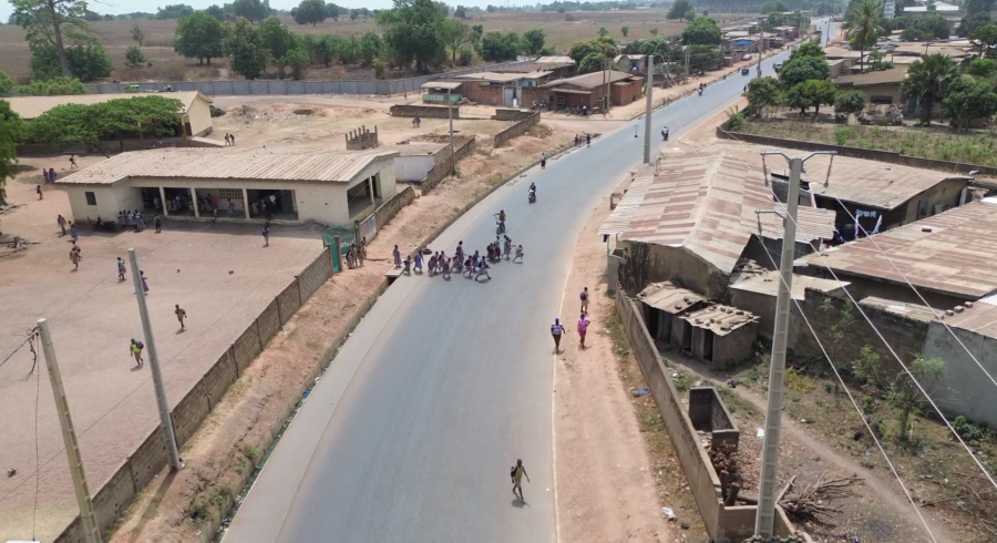 Drone view of a school gate with students trying to cross a recently asphalted road
